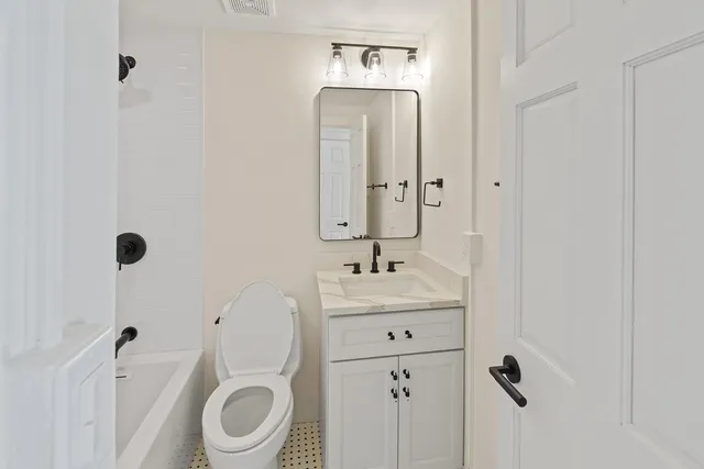 a bathroom with a toilet a sink a mirror and vanity