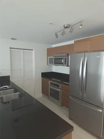 a kitchen with stainless steel appliances granite countertop a refrigerator and a sink