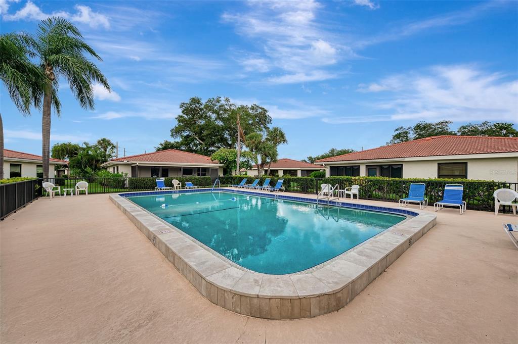 5103 Greencroft Road Sarasota, FL 34235 - Photo 2 of 25 a view of a swimming pool with lawn chairs under an umbrella