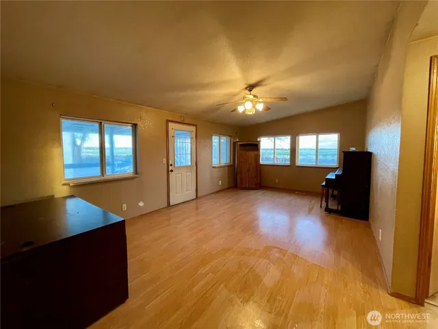 a view of an empty room with window and wooden floor
