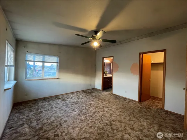 an empty room with windows and ceiling fan