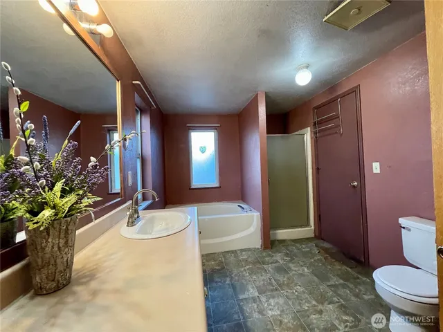 a spacious bathroom with a granite countertop sink a toilet a mirror and bathtub