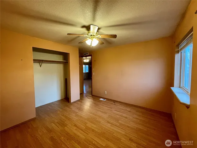 a view of an empty room with window and wooden floor
