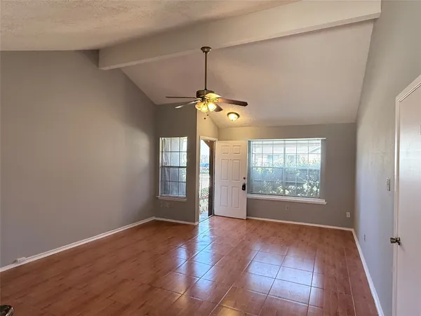 a view of an empty room with wooden floor and a window