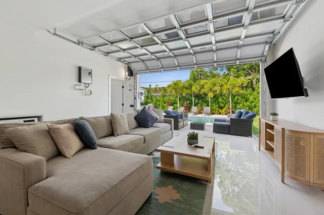 a living room with furniture a flat screen tv and a floor to ceiling window