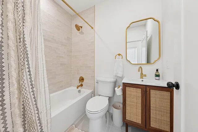 a bathroom with a toilet sink vanity tub and mirror