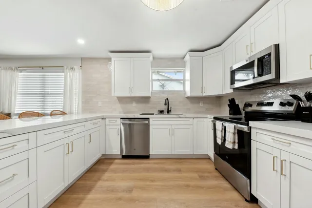 a kitchen with stainless steel appliances granite countertop a sink and cabinets with wooden floors