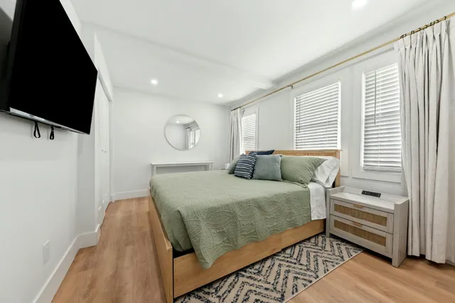 a spacious bedroom with a bed and a flat screen tv