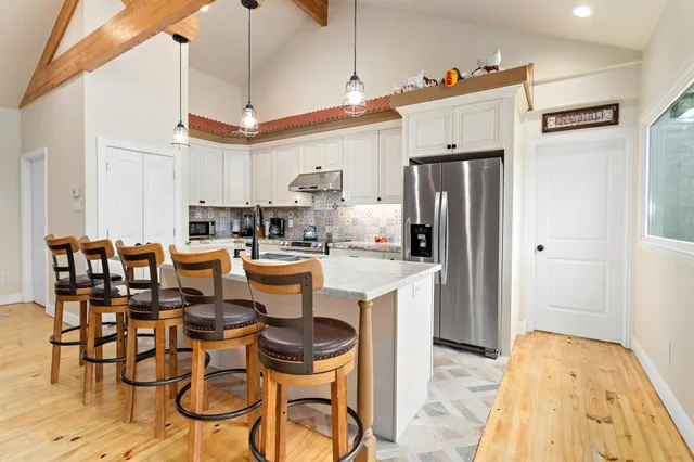 a kitchen with stainless steel appliances kitchen island granite countertop a stove a sink a dining table and chairs with wooden floor