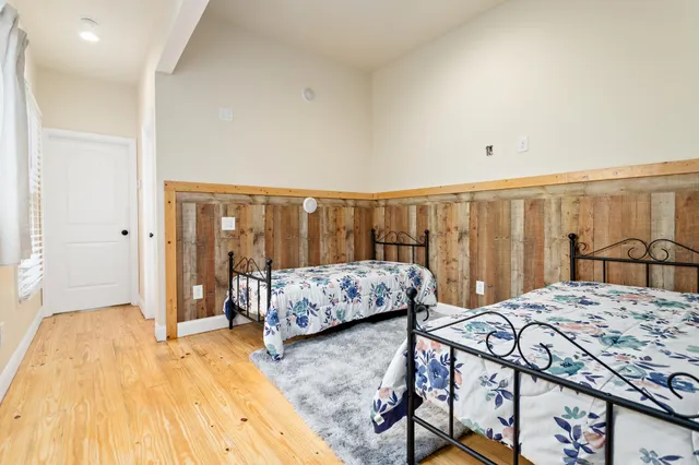a bedroom with two beds and wooden floor