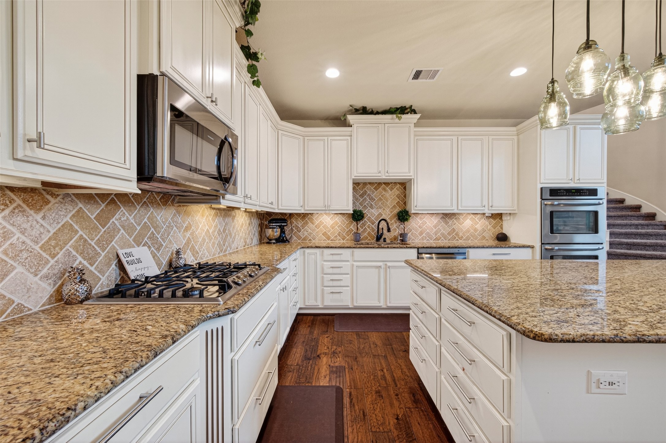 25611 Ellis Ridge Court Katy, TX 77494 - Photo 16 of 49 This kitchen features elegant white cabinetry, granite countertops, and a spacious island. It includes modern stainless steel appliances, a gas cooktop, double ovens, and a stylish tile backsplash. The open layout and pendant lighting create a warm, inviting atmosphere.