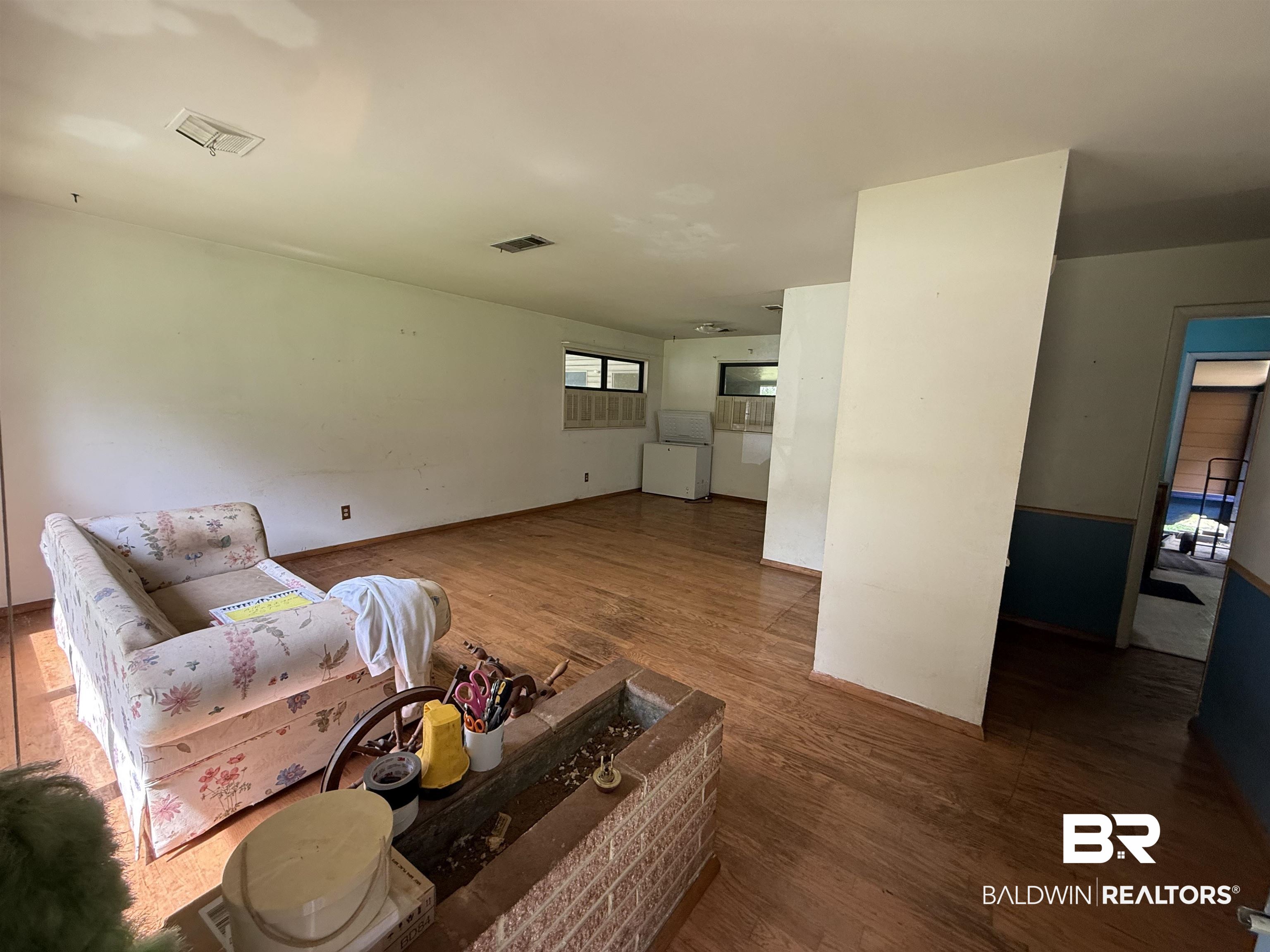 711 Wilshire Road Mobile, AL 36609 - Photo 2 of 11 Spacious interior featuring wood-finish flooring, white walls, and a brick hearth