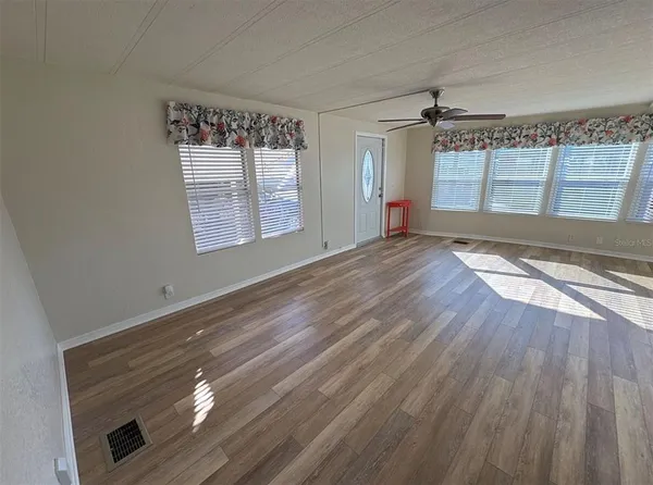 a view of an empty room with wooden floor and a window