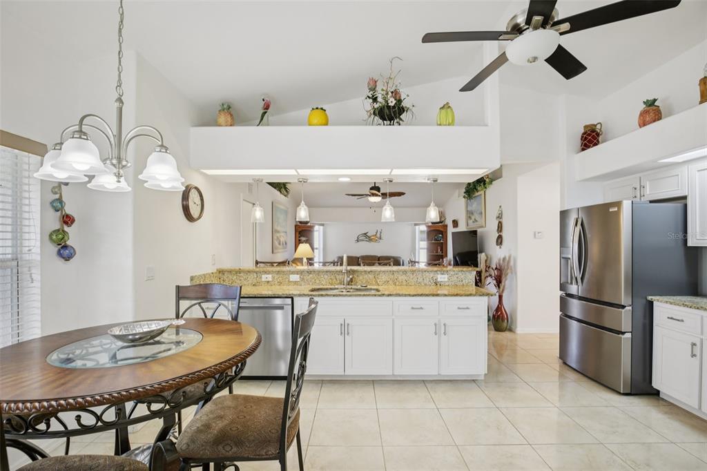 257 Medalist Road Rotonda West, FL 33947 - Photo 8 of 32 a kitchen with stainless steel appliances kitchen island granite countertop a sink a refrigerator and a dining table