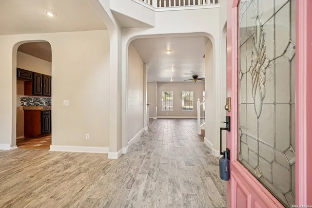 a view of an empty room with wooden floor and windows
