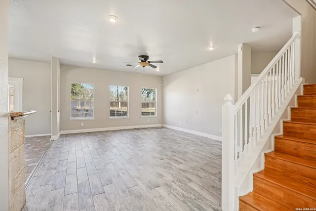 a view of an empty room with a window and wooden floor