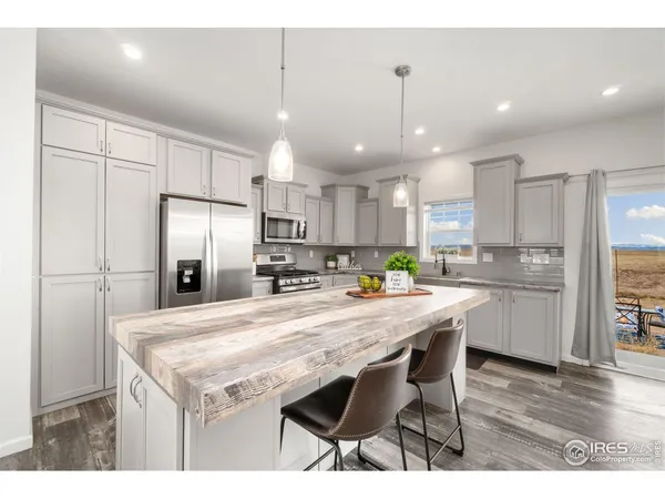 a kitchen with stainless steel appliances granite countertop a refrigerator a sink dishwasher a stove and white cabinets with wooden floor