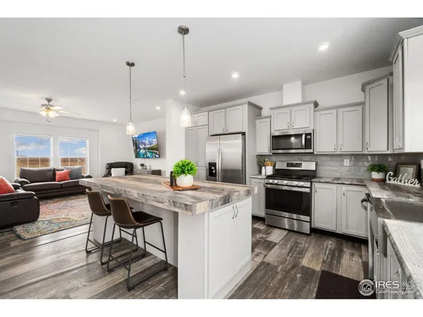 a kitchen with stainless steel appliances kitchen island granite countertop a table chairs and a refrigerator