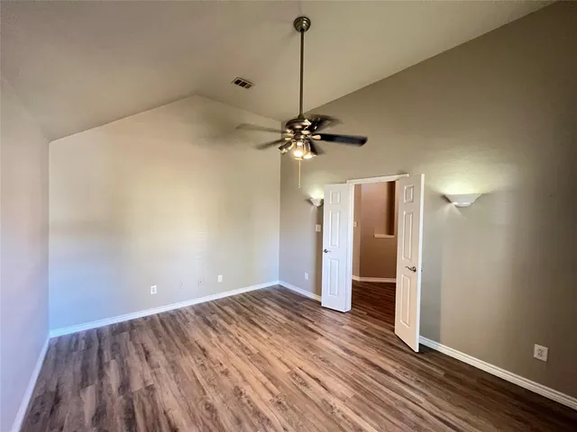 a view of a room with wooden floor a ceiling fan and staircase