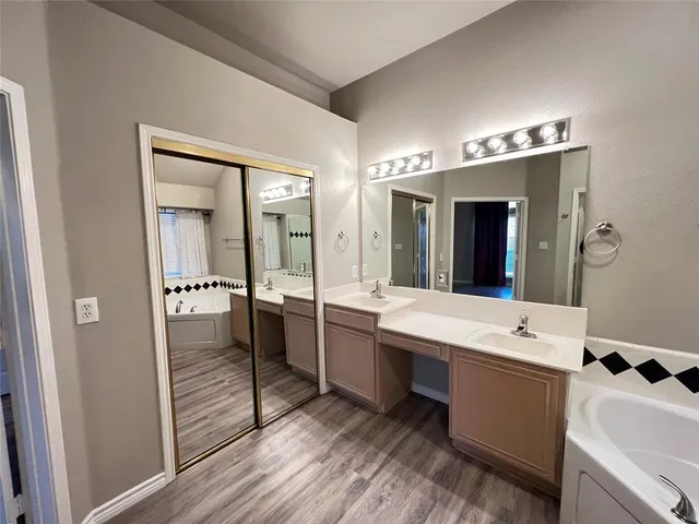 a bathroom with a double vanity sink mirror and bathtub