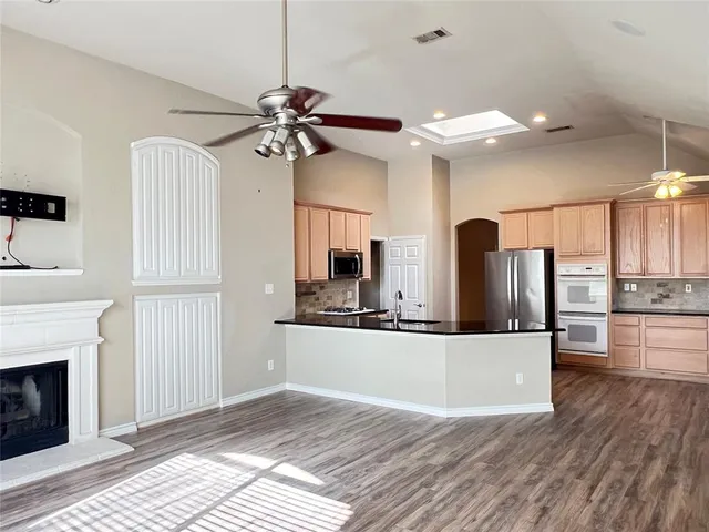 a view of a kitchen with wooden floor and a fireplace