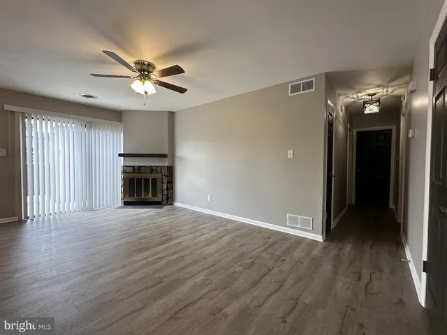 an empty room with wooden floor fan and windows