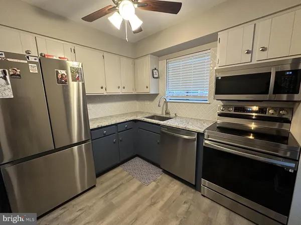 a kitchen with granite countertop a refrigerator stove and microwave