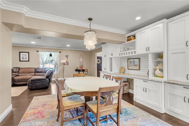 a kitchen with stainless steel appliances kitchen island granite countertop a table chairs sink and cabinets