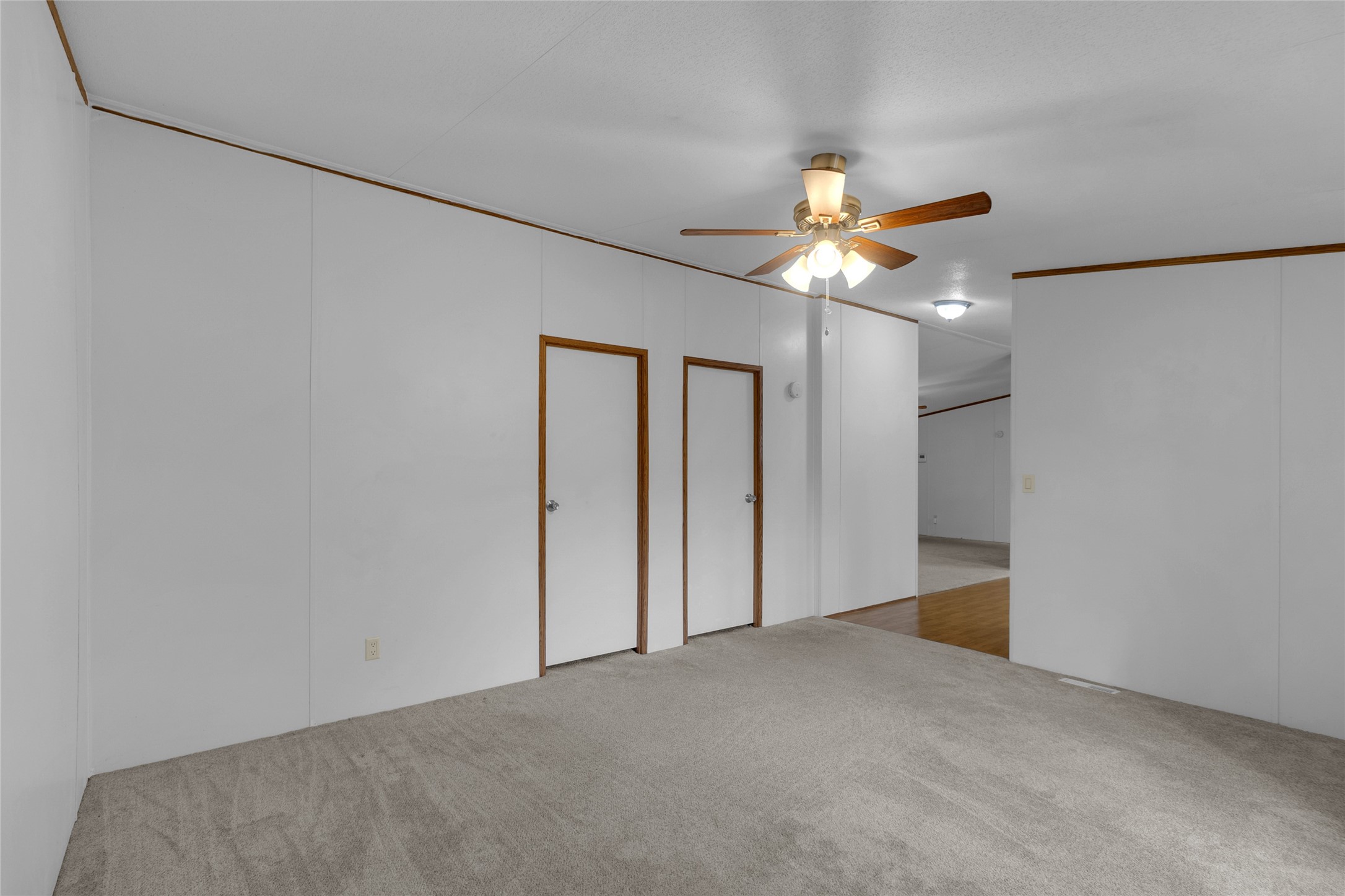 22094 Spear Road Porter, TX 77365 - Photo 28 of 45 Den room features neutral-toned carpeting, white walls with wood trim, a ceiling fan, and recessed lighting, offering a simple and functional space. The area includes two doors and a transition into the two additional bedrooms.