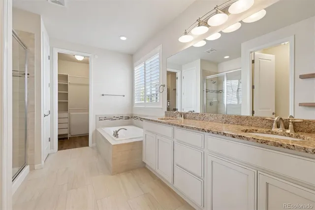 a spacious bathroom with a granite countertop sink a large mirror and a bathtub