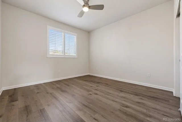 an empty room with wooden floor fan and windows