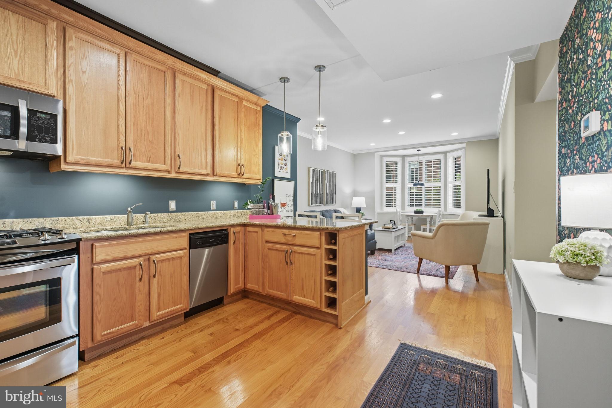 1669 Columbia Road Northwest, Unit 203 Washington, DC 20009 - Photo 18 of 18 a kitchen with granite countertop a stove a sink a refrigerator and white cabinets with wooden floor