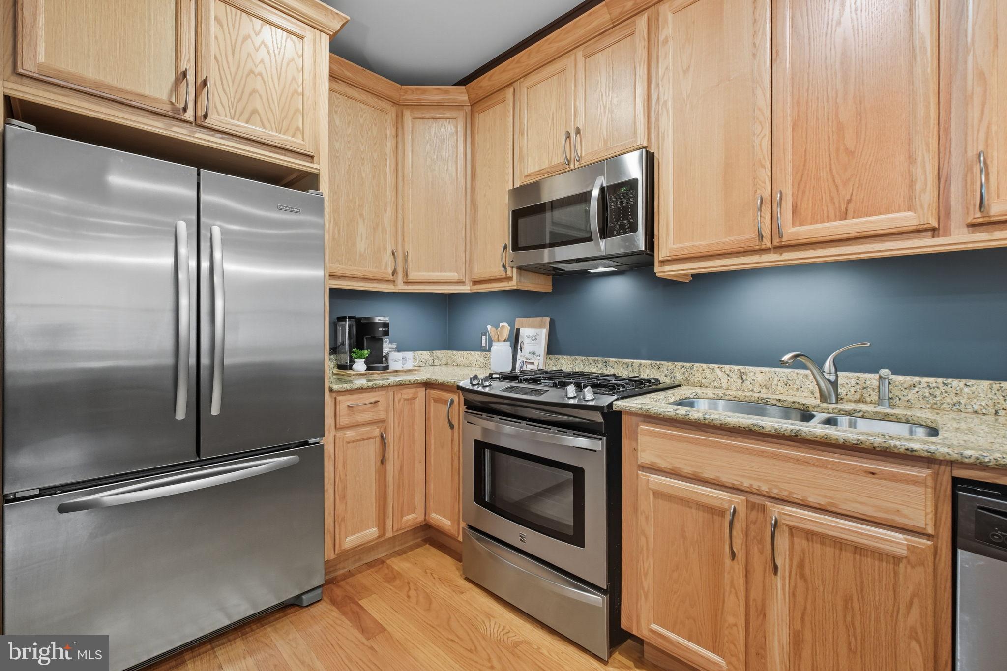1669 Columbia Road Northwest, Unit 203 Washington, DC 20009 - Photo 1 of 18 a kitchen with stainless steel appliances granite countertop a refrigerator a stove a sink and white cabinets with wooden floor