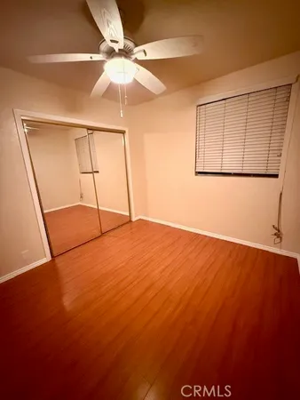 an empty room with wooden floor and fan