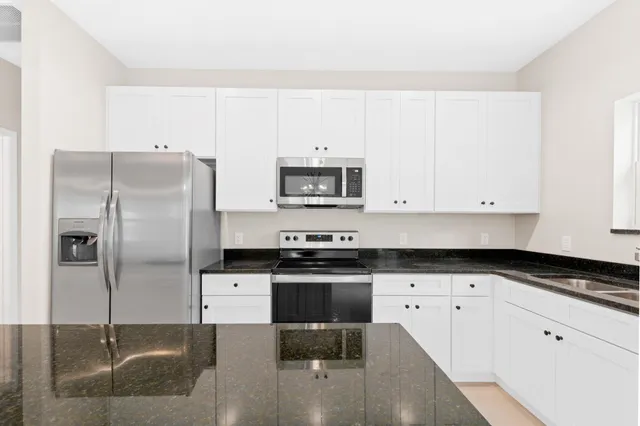 a kitchen with granite countertop a refrigerator stove and microwave