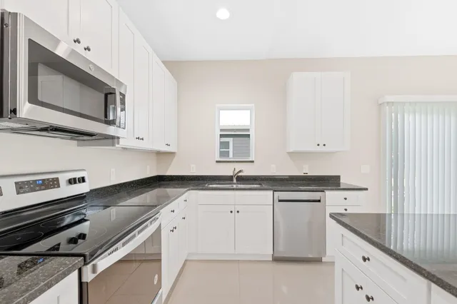 a kitchen with granite countertop a stove sink and microwave