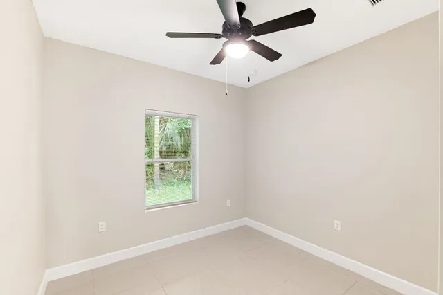 an empty room with a ceiling fan and carpet