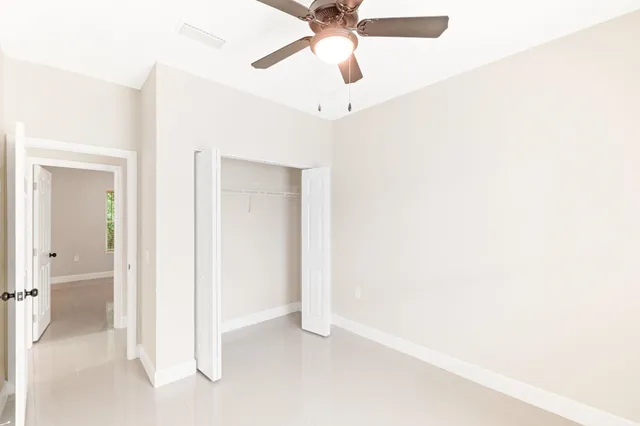 an empty room with windows and fan