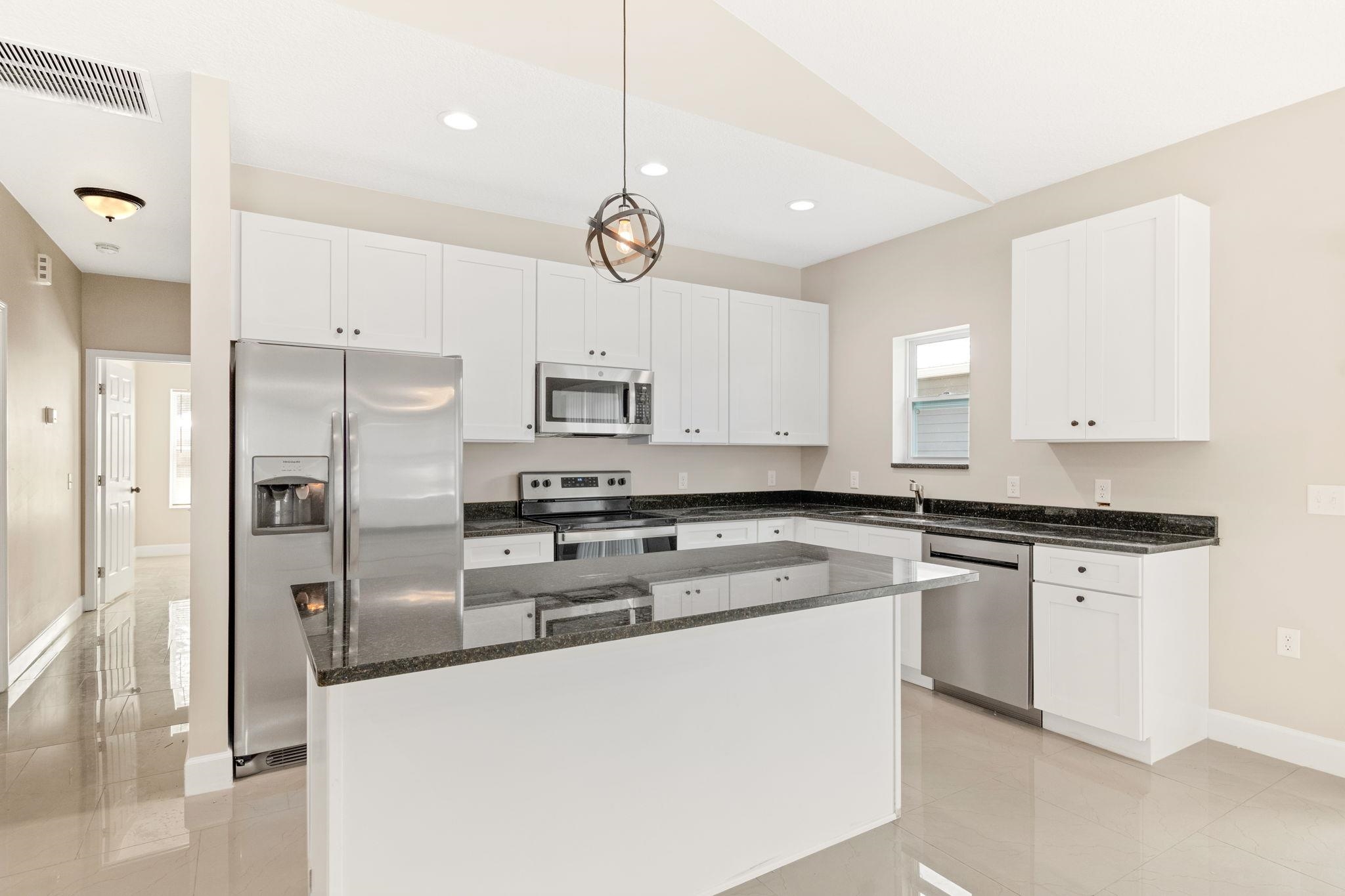 2770 Schaller Road St. Augustine, FL 32084 - Photo 9 of 29 a kitchen with stainless steel appliances granite countertop a sink a stove a refrigerator and white cabinets