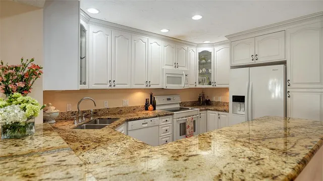 a kitchen with granite countertop stainless steel appliances white cabinets and a sink