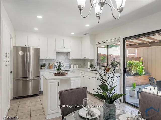 a kitchen with stainless steel appliances a microwave a stove a refrigerator a sink a dining table and chairs with wooden floor