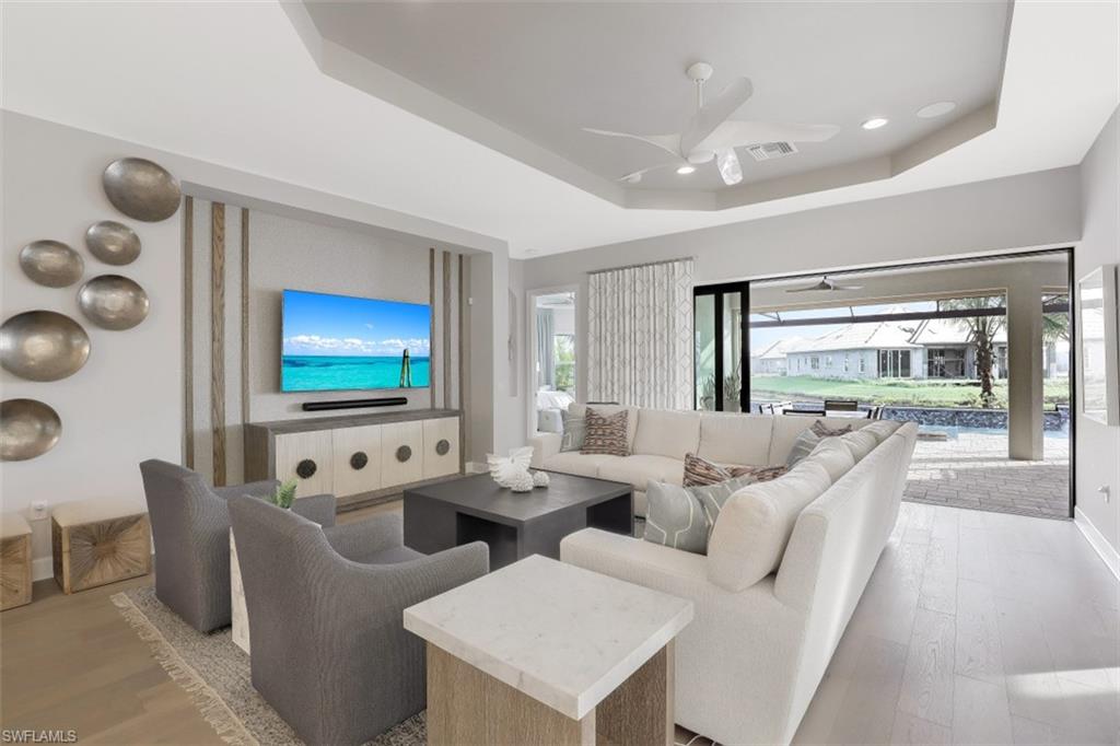 3258 Belon Lane Naples, FL 34114 - Photo 6 of 35 a living room with furniture a flat screen tv and a floor to ceiling window