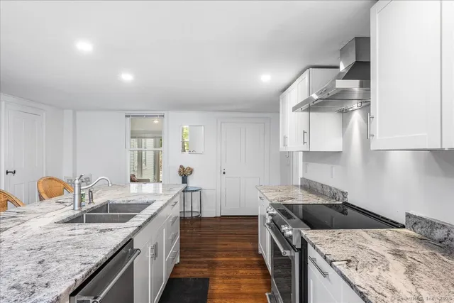 a kitchen with granite countertop a sink stove and cabinets