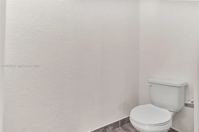 a white toilet sitting next to a white wall