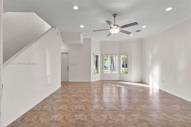 a view of an empty room with chandelier fan and windows