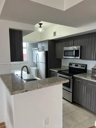 a kitchen with kitchen island a sink stove and refrigerator