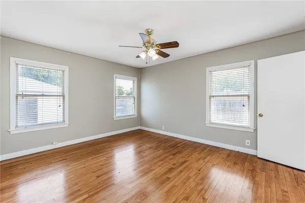 a view of an empty room with window and wooden floor