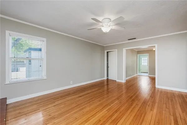 a view of an empty room with wooden floor and a window