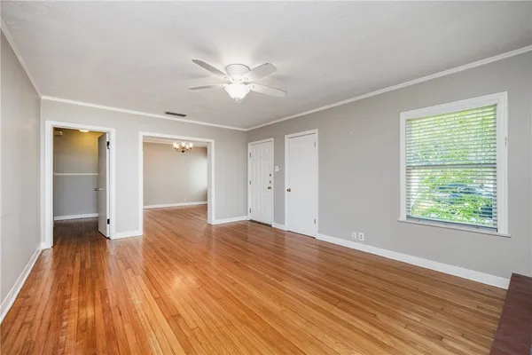 a view of an empty room with wooden floor and a window