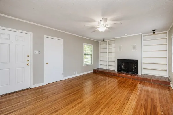an empty room with wooden floor fireplace and windows